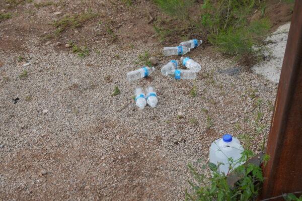 Water bottles left by humanitarians are common sights at breaches and open border gates along Arizona's border wall near Douglas on Aug. 25, 2022. (Allan Stein/The Epoch Times)