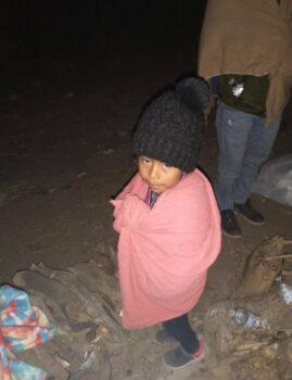 An unaccompanied child waits to be picked up by U.S. Border Patrol near a section of border wall fence in Arizona in March 2022. (Courtesy photo)