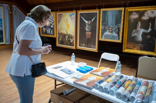 A lady looks at a photo album at the art exhibit of Truth, Compassion, and Tolerance, at the Moon Festival in Deerpark, New York, on Sept. 17, 2022. (Courtesy of New Century Film)