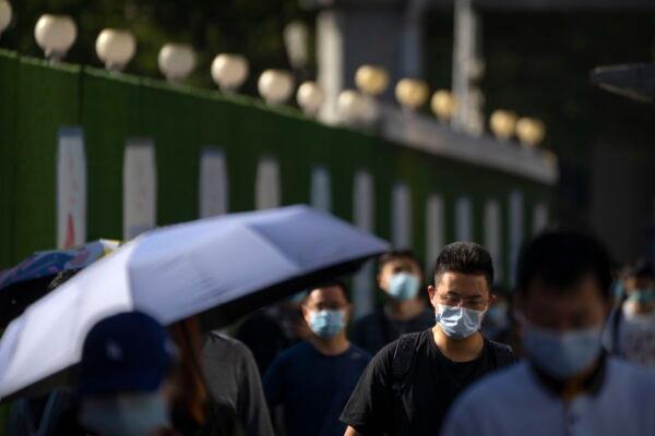 Commuters wearing face masks walk along a street in the central business district in Beijing on Sept. 1, 2022. (Mark Schiefelbein/AP Photo)
