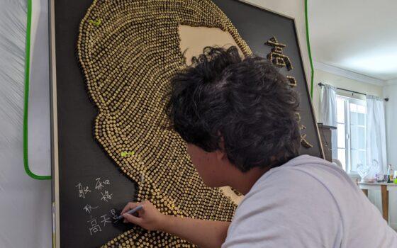Missing Chinese human rights lawyer Gao Zhisheng's son Gao Tianyu signing the floating sculpture of Gao Zhisheng on Aug. 13, 2022. (Xu Manyuan/Epoch Times)