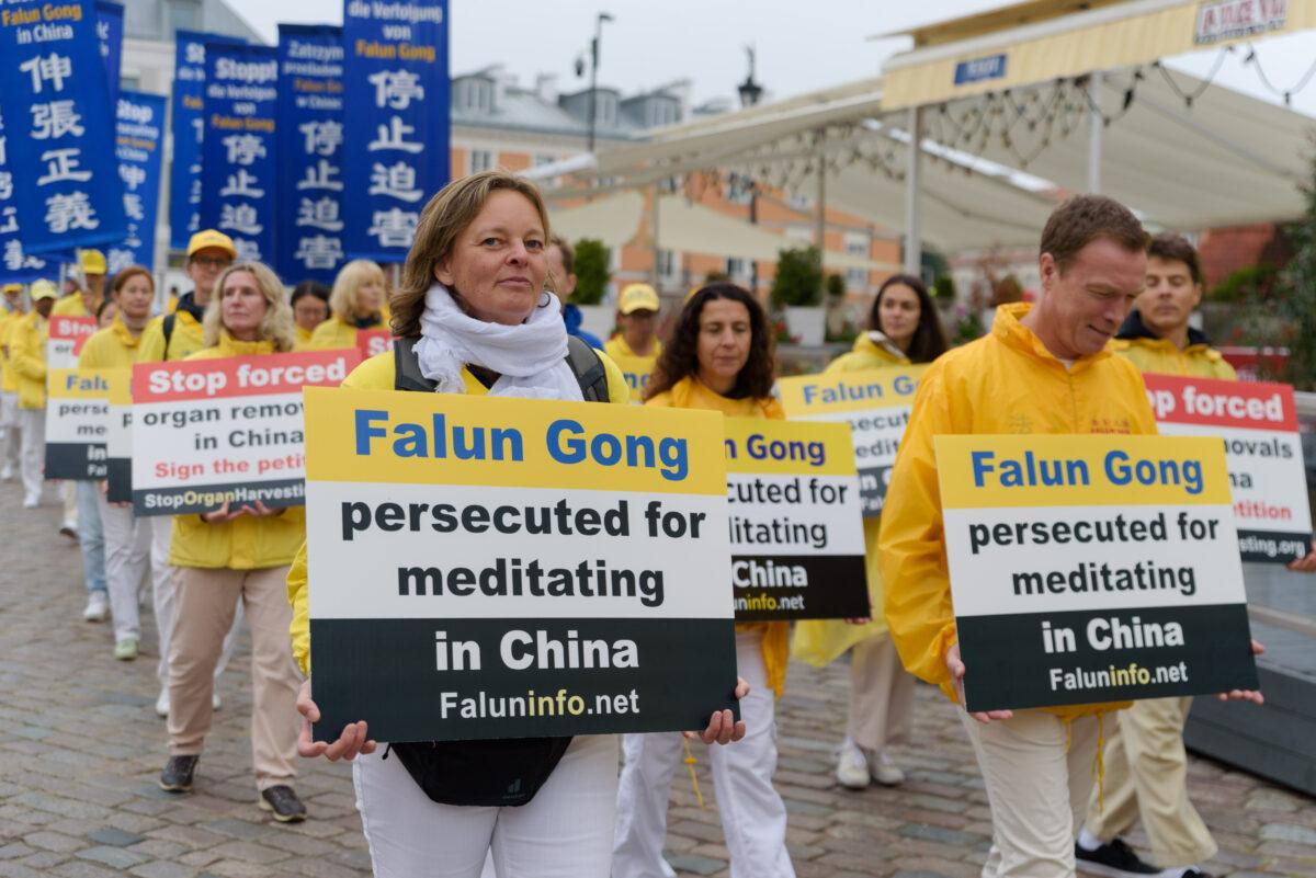 Falun Gong practitioners carry banners raising awareness about persecution in China during a march through the center of Warsaw, Poland, on Sept. 9, 2022. (Mihut Savu/The Epoch Times)