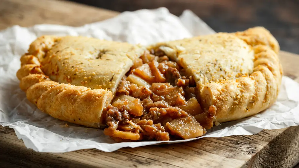 These savory handheld meals wrap a hot steak-and-potato filling in flaky shortcrust dough. (DronG/Shutterstock)