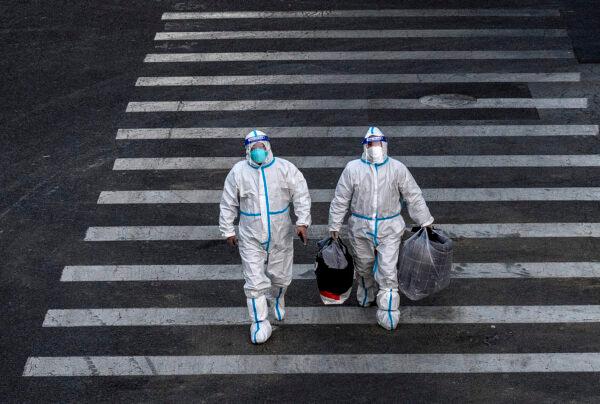 Epidemic control workers, dressed in protective gear to prevent exposure to COVID-19, are on their way to perform nucleic acid tests in an area with communities in lockdown in Beijing, China, on Dec. 1, 2022. (Kevin Frayer/Getty Images)