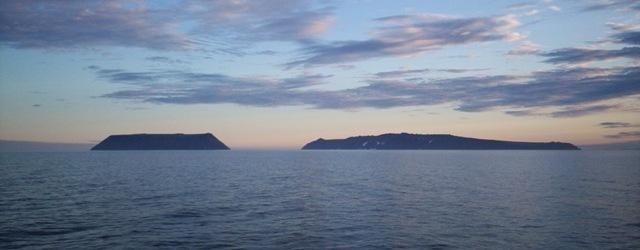 Little Diomede Island (left) and Big Diomede Island in the Bering Sea. (Dave Cohoe/<a href="https://commons.wikimedia.org/wiki/File:Diomede_Islands_Bering_Sea_Jul_2006.jpg">CC BY 3.0</a>)