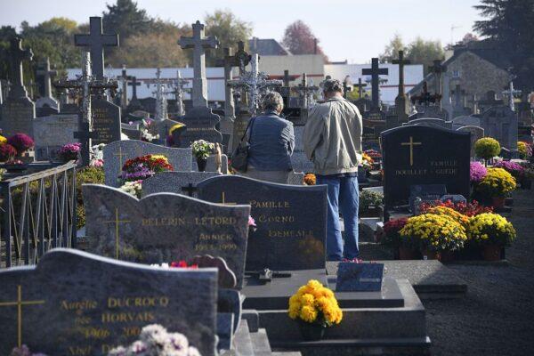 People pay their respects in front of a grave in a cemetery in the western city of Dinge, France, during All Saints' Day, on Nov. 1, 2016. (Damien Meyer/AFP via Getty Images)