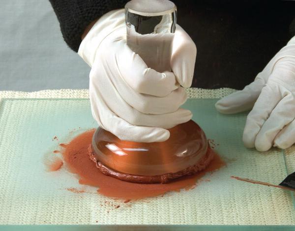 An artist uses a muller to grind the pigment paste until it becomes smooth; the smaller the pigment particles, the harder the grinding process.  (Courtesy of Natural Pigments)