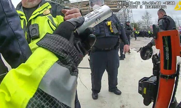 D.C. police officer Daniel Thau loads a 40-mm round with rubber projectiles into a launcher at the U.S. Capitol on Jan. 6, 2021. (Metropolitan Police Department/Screenshot via The Epoch Times)