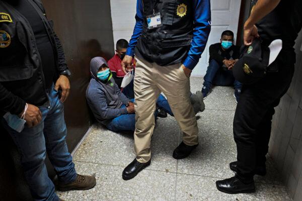 Police officers with alleged members of a human trafficking gang sit on the floor of a court after being arrested in Guatemala City on Oct. 24, 2022. (Johan Ordonez/AFP via Getty Images)
