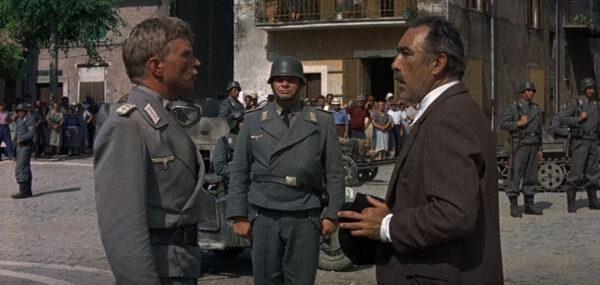 Capt. Von Prum (Hardy Krüger, L) matches wits with Bombolini (Anthony Quinn), in “The Secret of Santa Vittoria.” (United Artists)