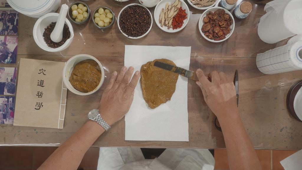 Huang Yong-he makes a plaster with herbs. (The Epoch Times)