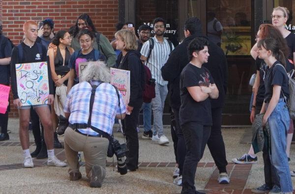 Students holding signs in support of transgender rights pose for a news photographer as part of a protest against Florida Gov. Ron DeSantis's efforts to curb diversity, equity, and inclusion programs in the state's public universities and colleges on Feb. 23, 2023. (Nanette Holt/The Epoch Times)