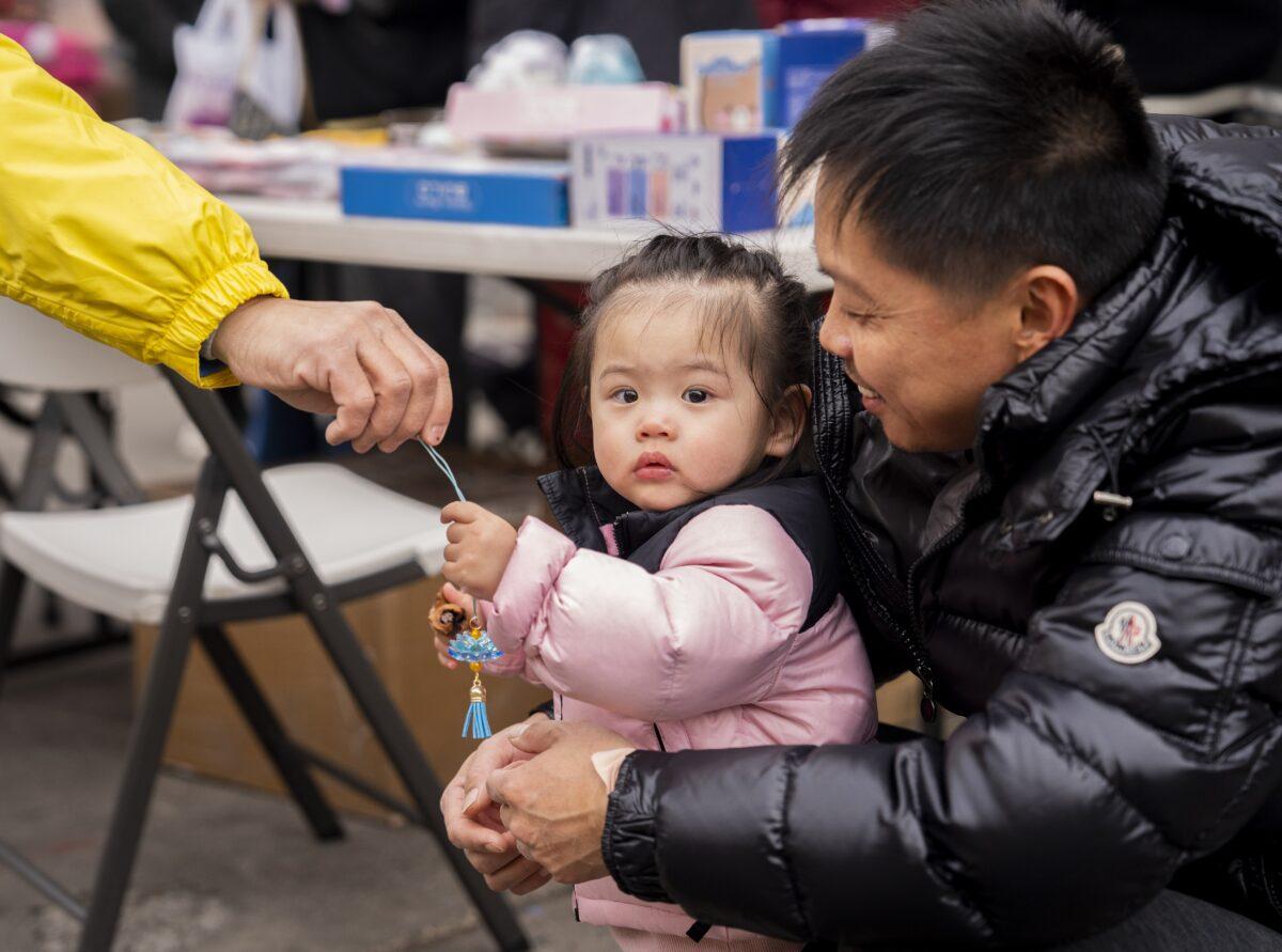 Bystanders watch Falun Gong practitioners march in a parade, in Brooklyn, N.Y., highlighting the persecution of their faith in China, on Feb. 26, 2023.(Chung I Ho/The Epoch Times)