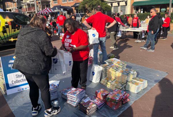 Teachers in red T-shirts from three unions pass out free children's books during "The Great Florida Read In" near the state Capitol, in Tallahassee, Fla. on March 14, 2023. (Nanette Holt/The Epoch Times)