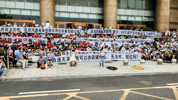 People hold banners and chant slogans during a protest at the entrance to a branch of China's central bank in Zhengzhou, Henan Province, China, on July 10, 2022, after four rural banks stopped allowing customers to withdraw cash since April 2022. (Yang/AP Photo)