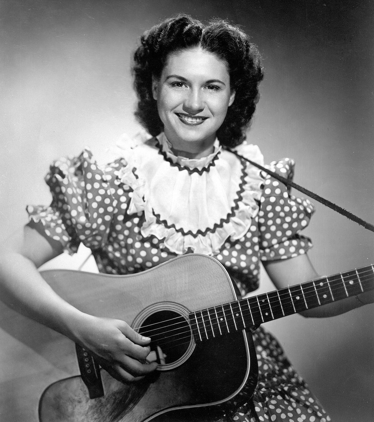 Kitty Wells posing with her guitar in 1956. Photograph by Walden S. Fabry in Nashville, Tenn. The Sun Newspaper Photograph Collection, Library of Congress. (Public Domain)