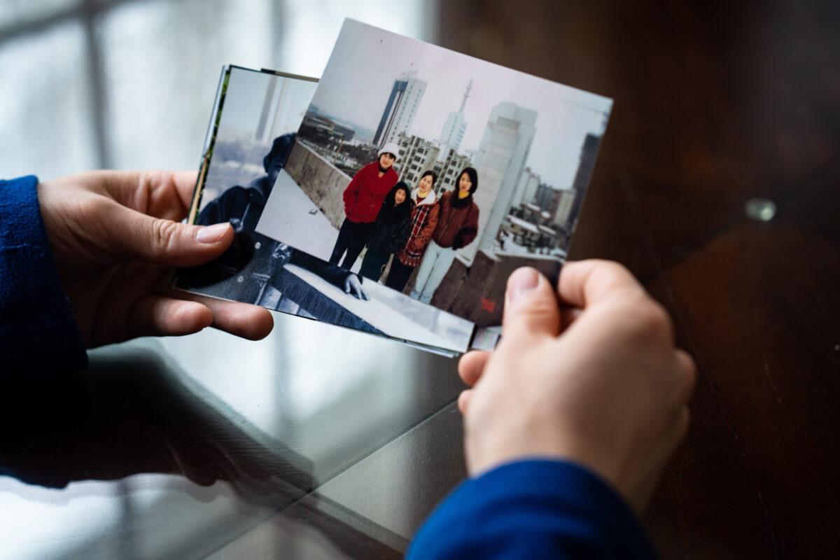Steven Wang, Shen Yun principal dancer, looks at a photograph of himself with his mother and sisters, at his home in New York state on March 31, 2023. (Samira Bouaou/The Epoch Times)