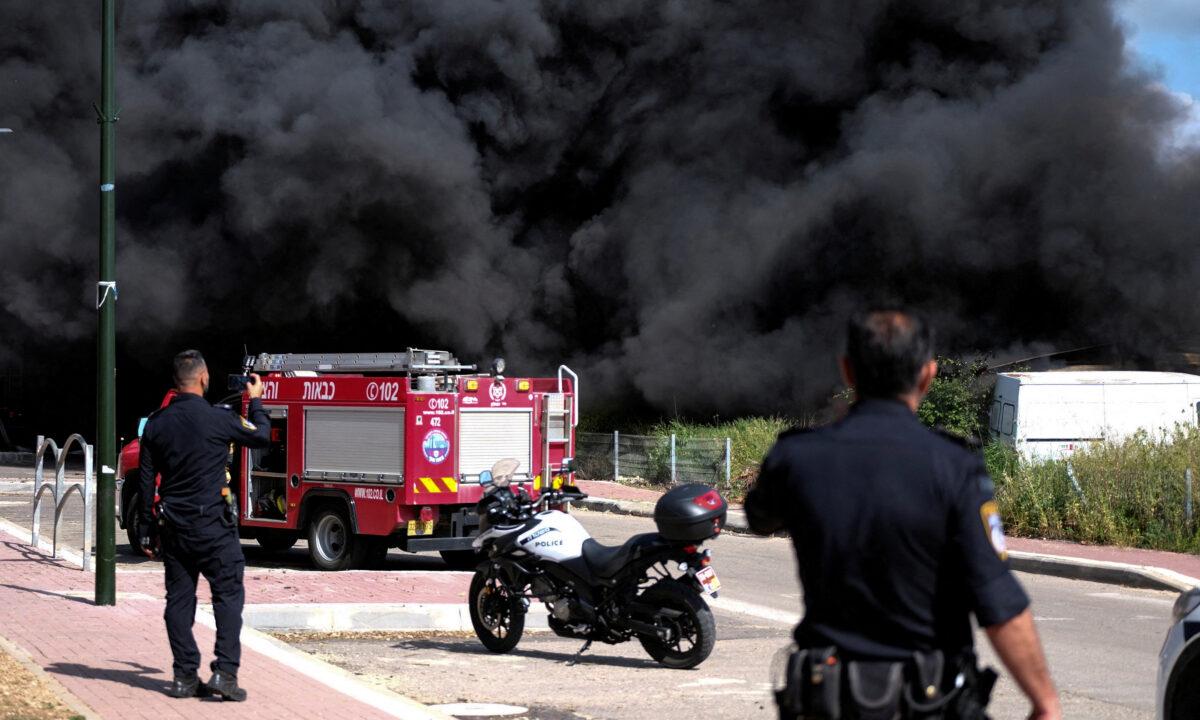 Israeli policemen stand next to smoke from a fire following incoming rockets from Lebanon to Israel in Bezet, northern Israel, on April 6, 2023. (Fadi Amun/Reuters)