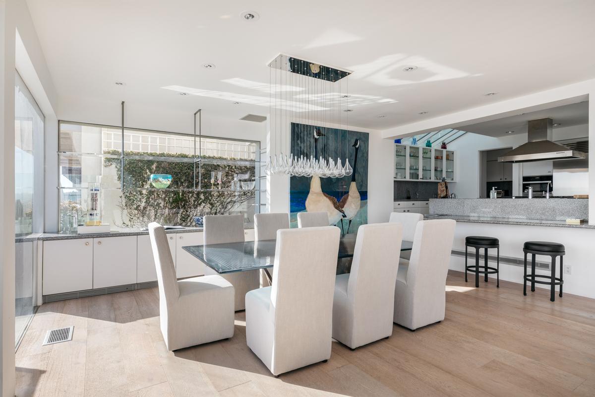 The dining room is conveniently adjacent to the kitchen and has dramatic hanging lighting, walls ideal for displaying large artwork, and clear views of the ocean. (Courtesy of Stirling Reed and toptenrealestatedals.com)