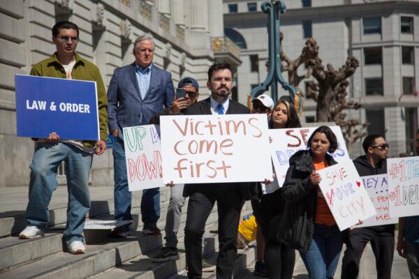 People hold signs at a rally in front of San Francisco City Hall on April 16, 2023, to call for safer streets without open-air drug markets. (Lear Zhou/The Epoch Times)