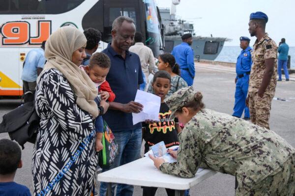 A picture taken on April 30, 2023, shows a member of the US military assisting US nationals fleeing war-torn Sudan in boarding an evacuation vessel in Port Sudan amid ongoing deadly clashes between Army forces and paramilitaries. (Photo by AFP) (Photo by -/AFP via Getty Images)