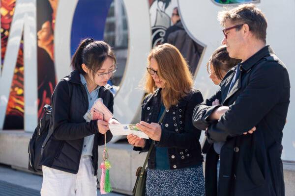 A Falun Gong adherent introduces the spiritual practice to people in downtown Toronto on May 6, 2023. (Evan Ning/The Epoch Times)