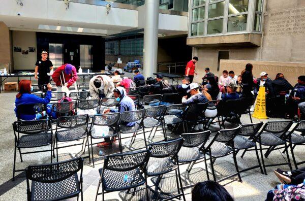 Newly arrived asylum-seekers in Denver's Reception Center wait for instructions before they travel by charter bus to other U.S. states and cities. (Allan Stein/The Epoch Times)