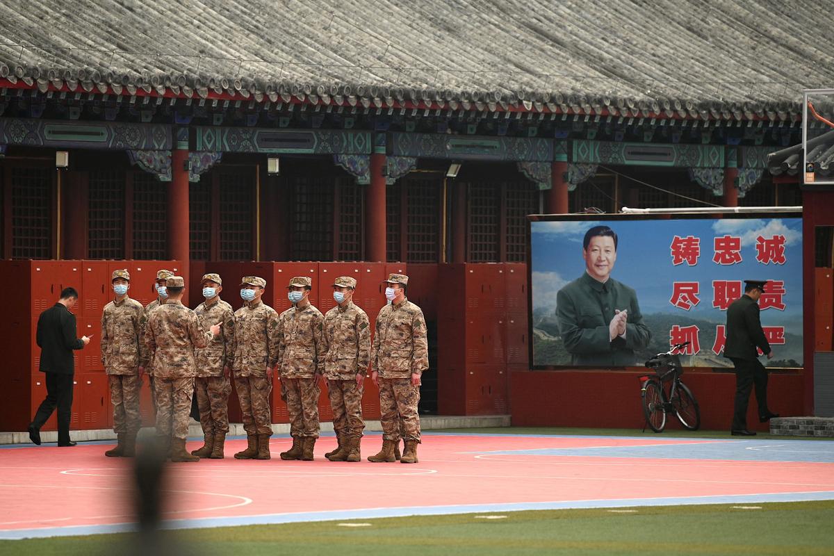 Security personnel stand guard at the entrance to the Forbidden City near an image of Chinese leader Xi Jinping (R) as the closing session of the National Peoples Congress (NPC) takes place at the Great Hall of the People nearby in Beijing on March 11, 2022. (Photo by Noel Celis / AFP via Getty Images)