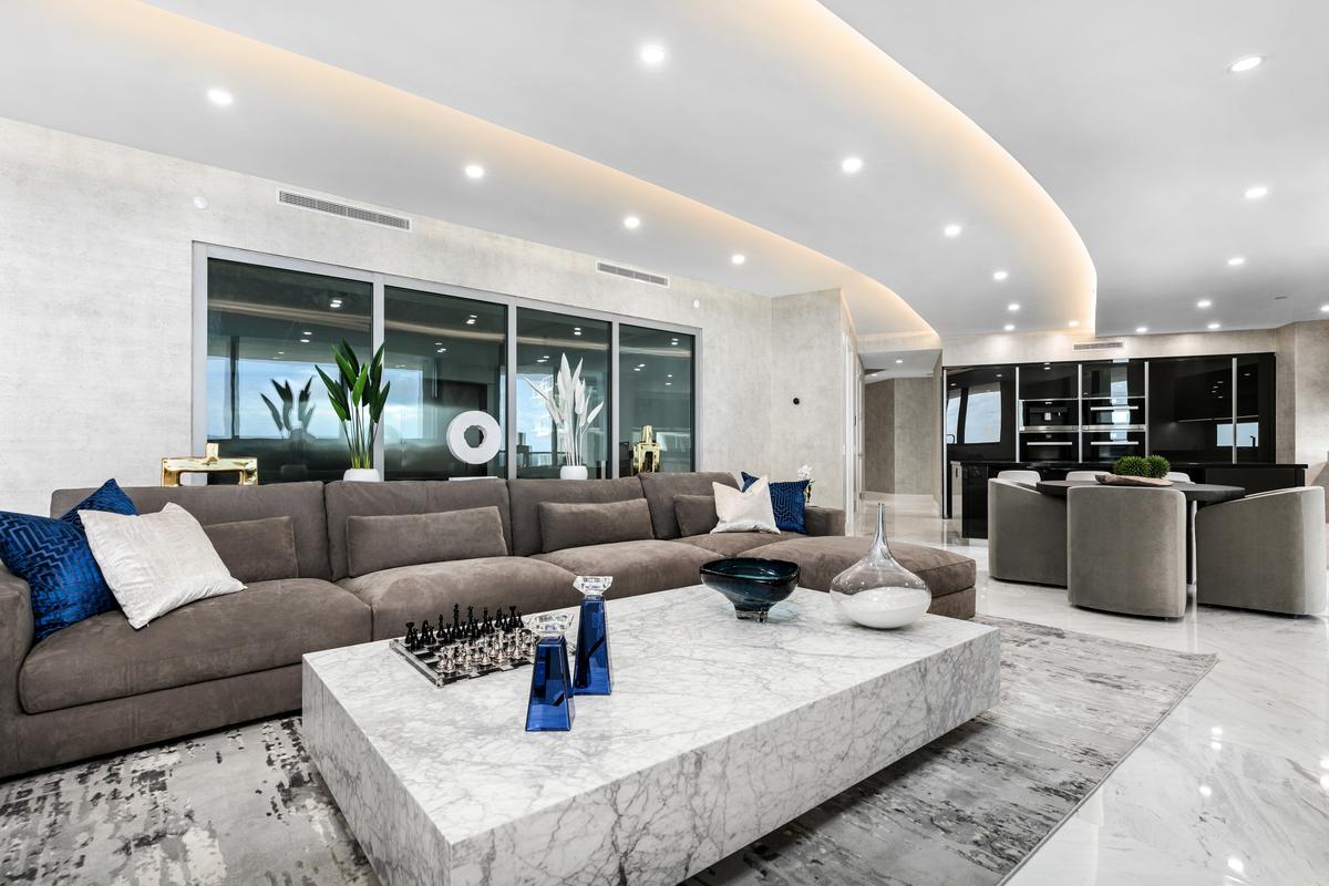 The airy, very welcoming living room backs up to the glass-walled car garage, where the owner can display their vintage or exotic automobiles. (Courtesy of The Carroll Group)