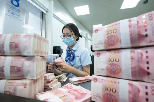 A bank employee counts 100-yuan notes at a counter in Nantong, Jiangsu Province, China, on June 13, 2023. (STR/AFP via Getty Images)