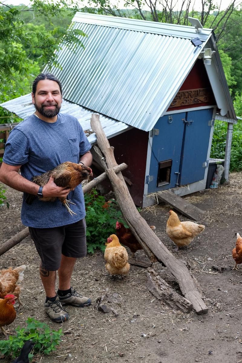 Juan Camacho wrangles his flock of chickens outside the little hen house overlooking the downtown city skyline. (Annie Holmquist)