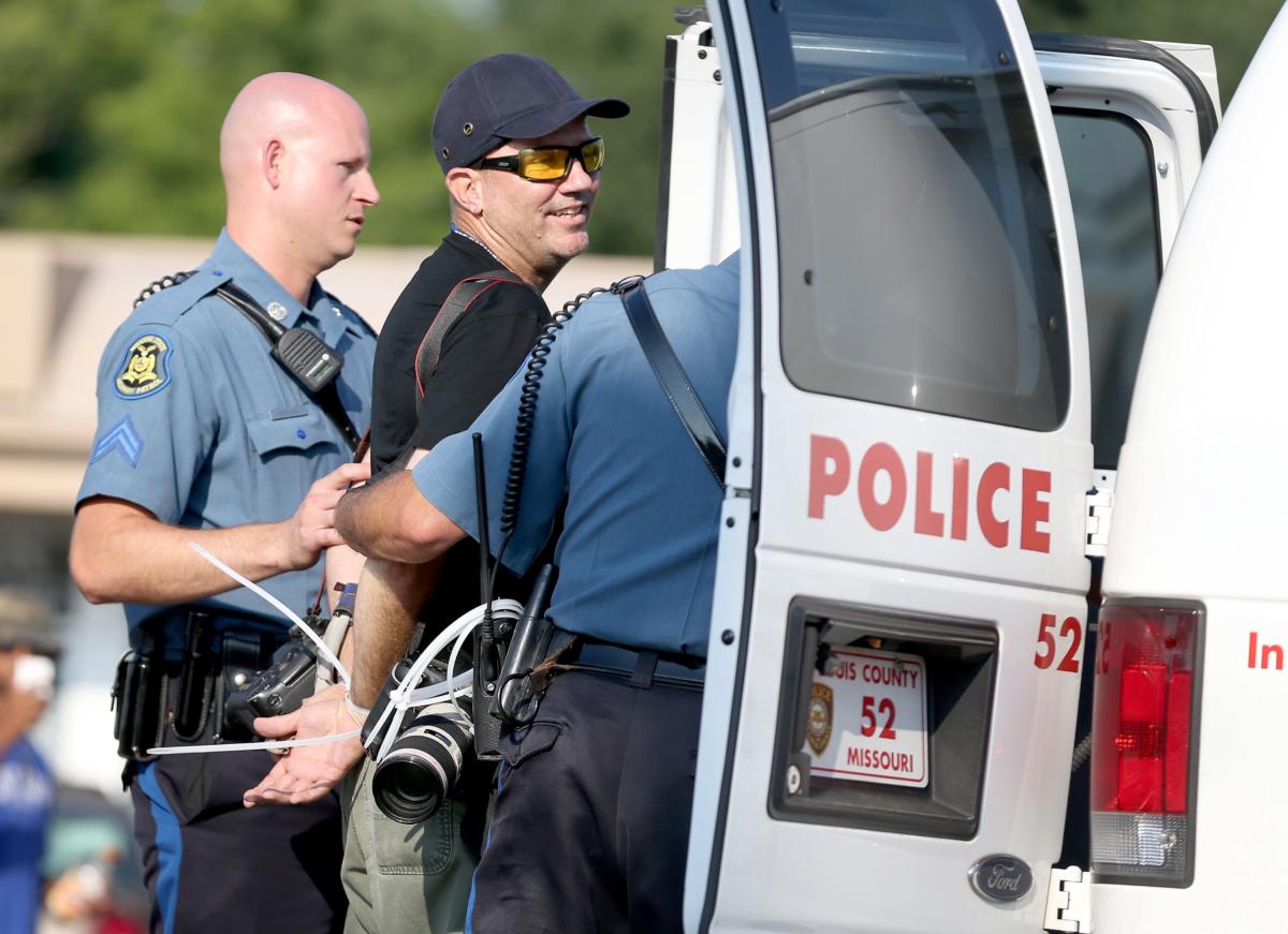 Getty Images staff photographer Scott Olson is placed into a paddy wagon after being arrested by police as he covers the demonstration following the shooting death of Michael Brown in Ferguson, Missouri, on Aug. 18, 2014. (Joe Raedle/Getty Images)