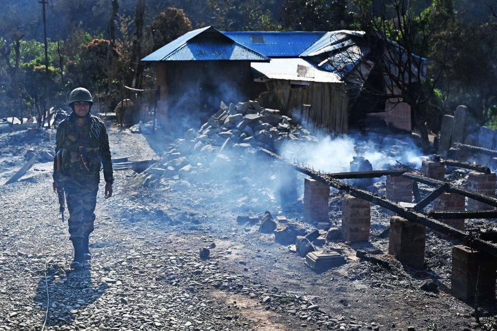 An Indian army soldier walks past the remains of a house that was set on fire by a mob in an area hit by ethnic violence, in Senapati district, in India's Manipur state, on May 8, 2023. (Arun Sankar/AFP via Getty Images)