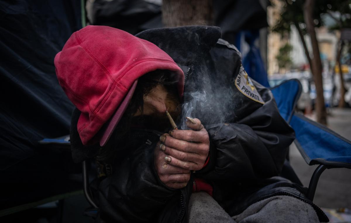 Spencer from the state of Washington lights up marijuana laced with drugs in front of his tent on the streets of the Tenderloin District of San Francisco, Calif., on Feb. 23, 2023. (John Fredricks/The Epoch Times)