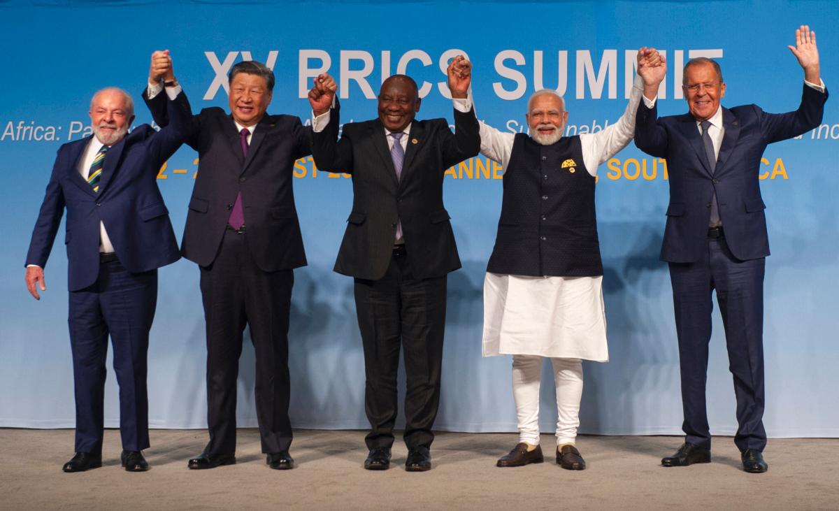 (L–R) Brazilian President Luiz Inácio Lula da Silva, Chinese leader Xi Jinping, South African President Cyril Ramaphosa, Indian Prime Minister Narendra Modi, and Russian Foreign Minister Sergei Lavrov raise their arms as they pose for a group photograph at the BRICS Summit in Johannesburg on Aug. 23, 2023. (Alet Pretorius/AFP via Getty Images)