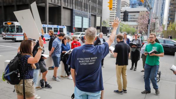Supporters of Pastor Tim Stephens sing hymns and pray outside the Calgary Courts Centre in Calgary, Alberta, on May 17, 2021. (Jeff McIntosh/The Canadian Press)