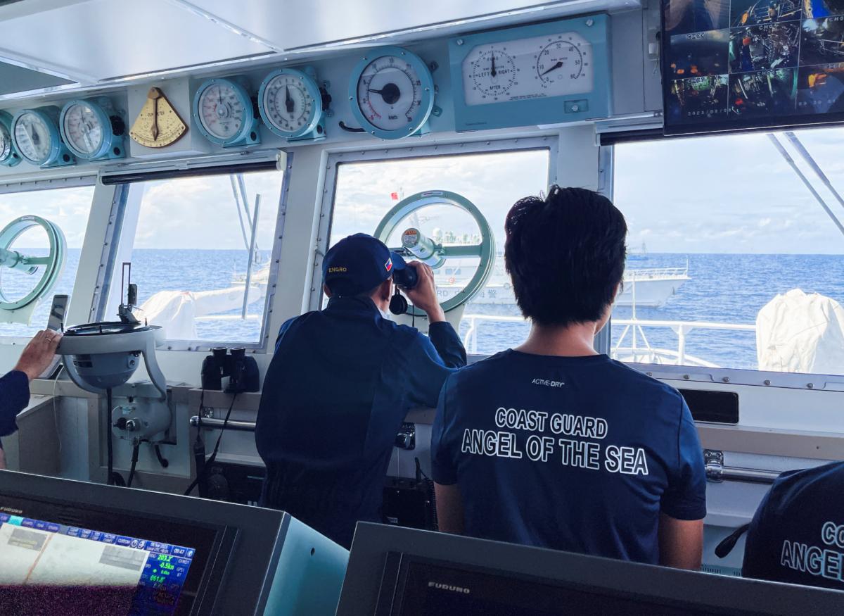 A member of the Philippines Coast Guard uses binoculars to check on a China Coast Guard vessel, during a resupply mission for troops stationed at a grounded Philippines ship, in the South China Sea, on Sept. 8, 2023. (Jay Ereno/Reuters)