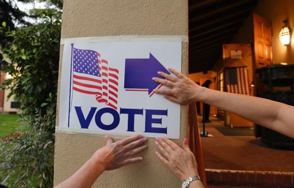 Poll workers attach a sign as they set up a voting station at Laguna Beach City Hall in Laguna Beach, California, on Nov. 6, 2018. (Robyn Beck/AFP via Getty Images)
