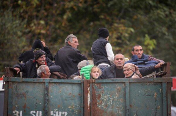 Refugees from the Nagorno-Karabakh region ride in the back of a truck as they arrive in the border village of Kornidzor, Armenia, on Sept. 26, 2023. (Irakli Gedenidze/Reuters)