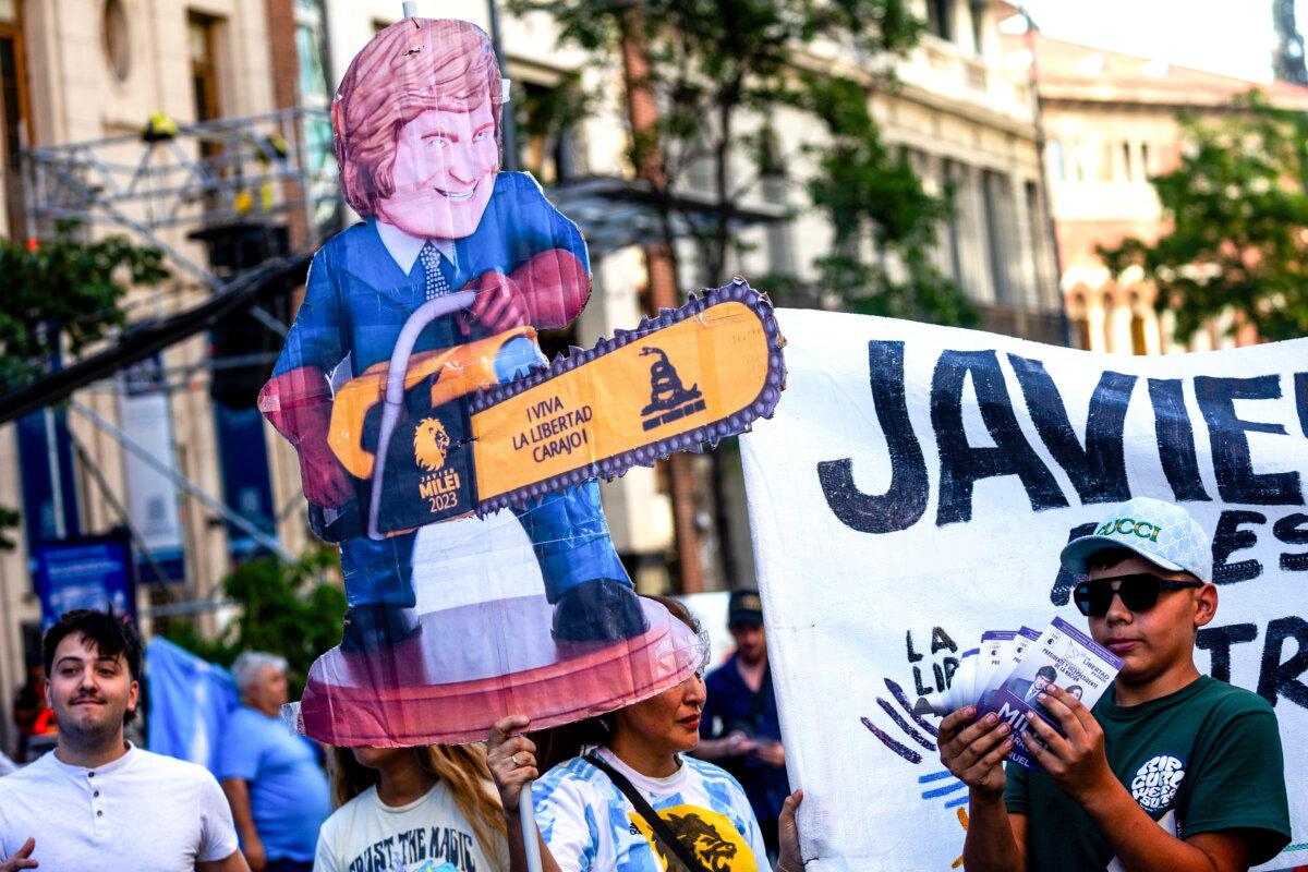 Supporters of presidential candidate Javier Milei hold a sign depicting Milei wielding a chainsaw, prior his closing rally before the runoff election in Cordoba, Argentina, on Nov. 16, 2023. (Tomas Cuesta/Getty Images)