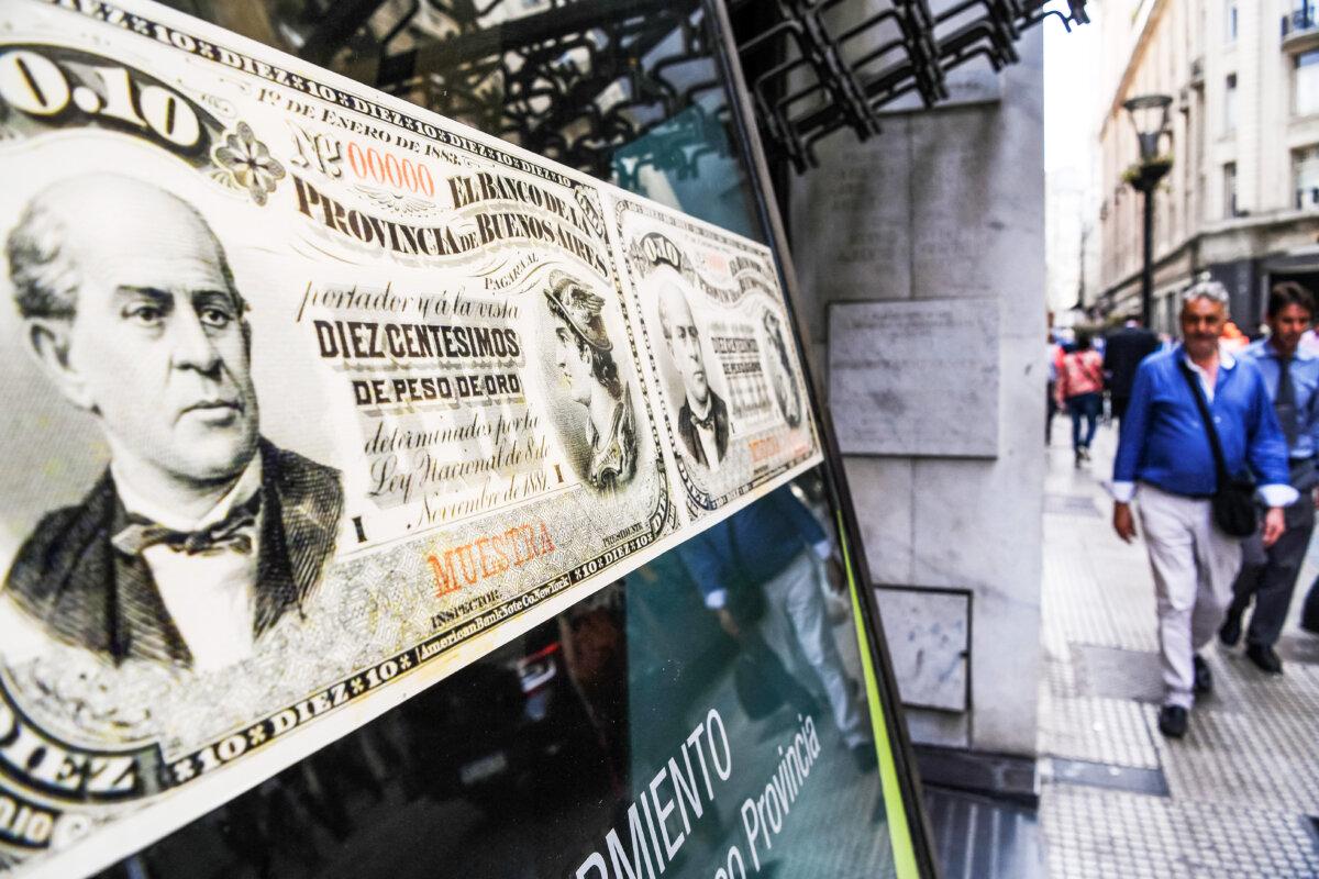 People walk past a bank branch decorated with images of old Argentine peso bills, in Buenos Aires, Argentina, on Sept. 26, 2018. (Eitan Abramovich/AFP via Getty Images)