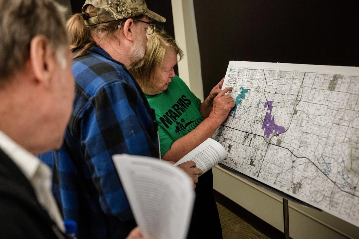 People look over a map of land suspected of being leased for solar energy production, while others gather for a meeting of the Mid Missouri Landowner Alliance to discuss opposition to solar farm projects in the Callaway County area in New Bloomfield, Mo., on March 15, 2023. (Brendan Smialowski/AFP via Getty Images)