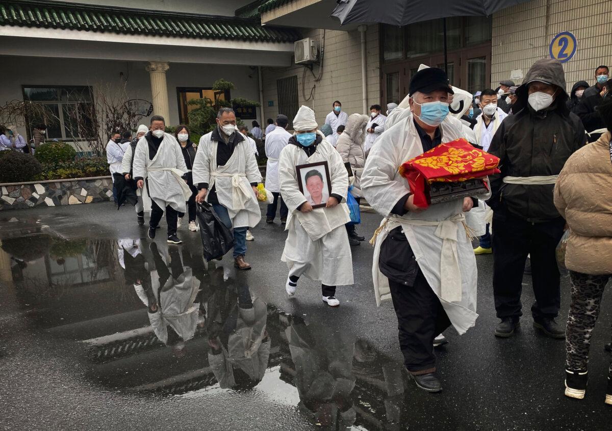 A mourner carries the cremated remains of a loved one as he and others wear traditional white funeral clothing during a funeral in Shanghai on Jan. 14, 2023. (Kevin Frayer/Getty Images)