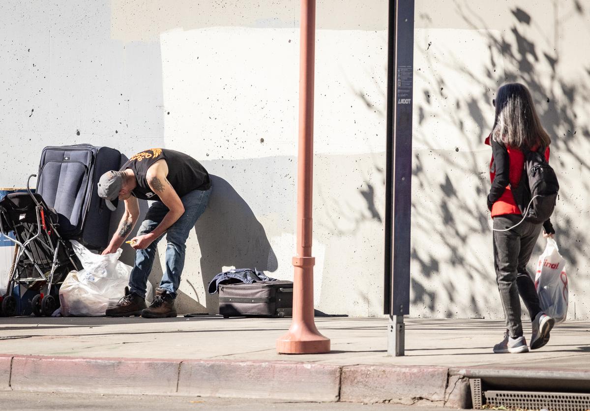 People pass homeless individuals in Los Angeles. Calif., on Jan. 11, 2024. (John Fredricks/The Epoch Times)