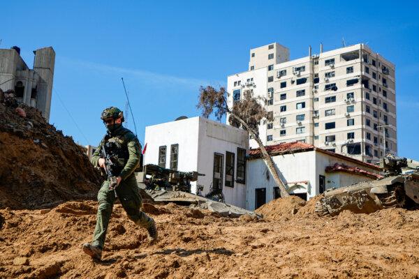 An Israeli soldier runs down a crater-like hole giving way to a tunnel entrance, leading to where the military says it discovered tunnels underneath the main headquarters of UNRWA, the U.N. agency for Palestinian refugees, in Gaza on Feb. 8, 2024. (AP Photo/Ariel Schalit)