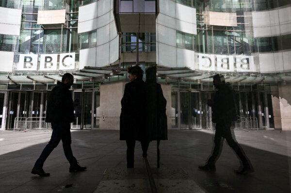 A pedestrian is reflected in the glass facade while walking past the BBC Headquarters at the Broadcasting House in central London, on Oct. 6, 2022. (Justin Tallis/AFP via Getty Images)