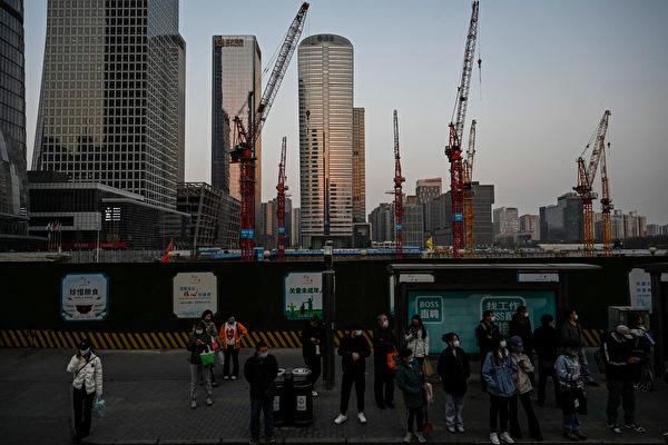 People wait for buses at a bus stop near a construction site in the central business district in Beijing on March 26, 2023. (Jade Gao/AFP/Getty Images)