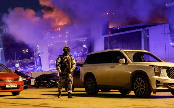 A Russian law enforcement officer walks near the burning Crocus City Hall concert venue following a mass shooting in Moscow on March 22, 2024. (Maxim Shemetov/Reuters)