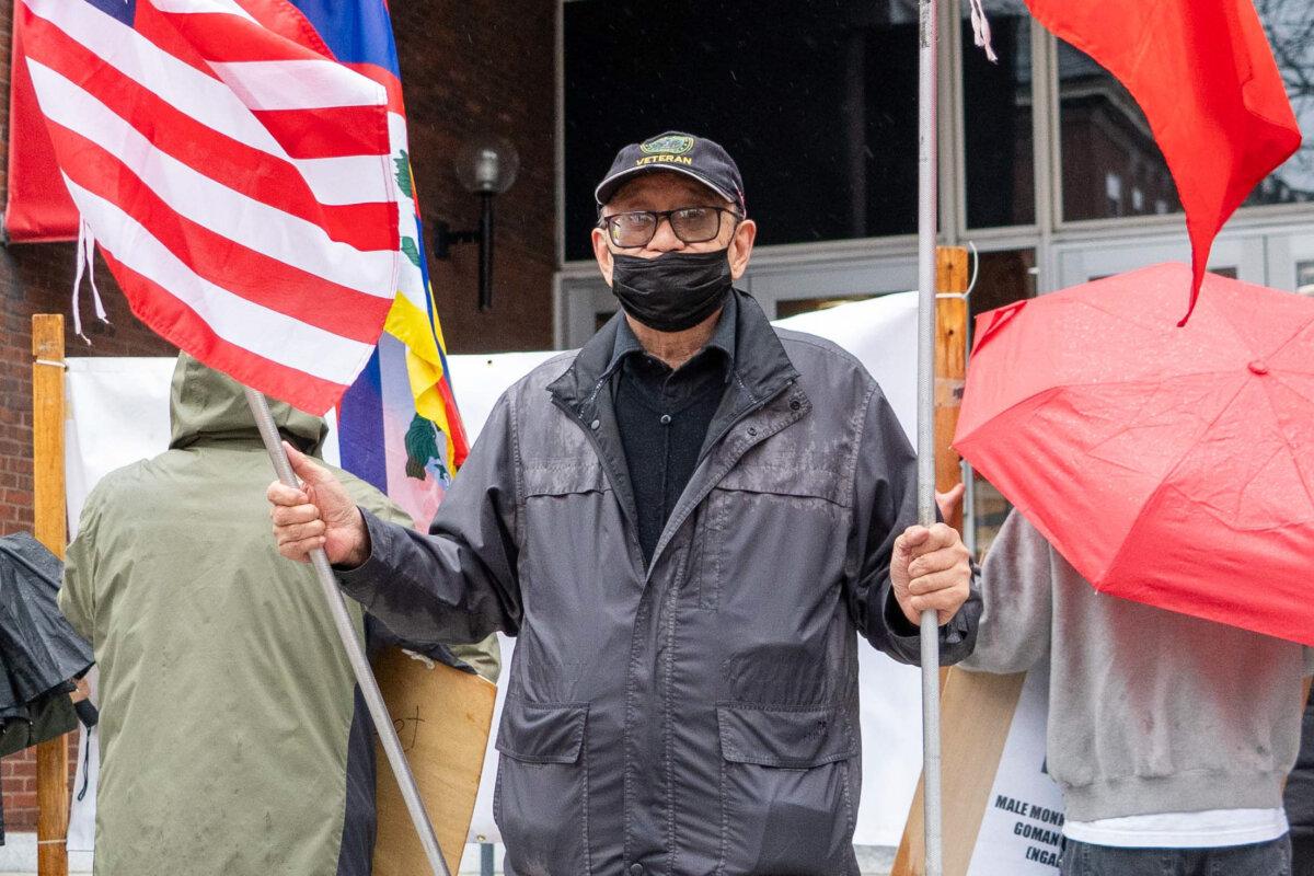 Che Chungchi, a protester, holds U.S. and Taiwanese flags at Harvard Kennedy School in Cambridge, Mass., on April 20, 2024. (Learner Liu/The Epoch Times)
