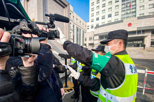 A policeman covers a camera to stop journalists from recording footage outside the Shanghai Pudong New District People's Court, where Chinese citizen journalist Zhang Zhan is set for trial in Shanghai on Dec. 28, 2020. (Leo Ramirez/AFP via Getty Images)